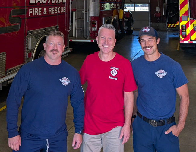 Ray Austin standing beside men in matching red firefighter shirts